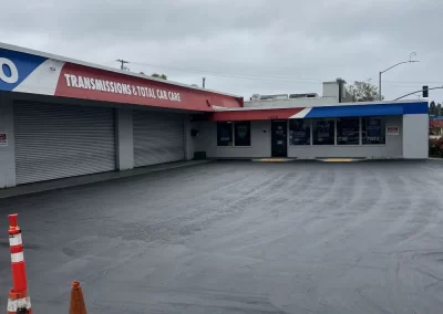 Auto repair shop with a red roof, empty parking lot, and two orange traffic cones in the foreground.