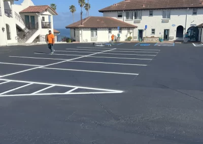 Freshly painted empty parking lot in front of white buildings with red roofs on a sunny day.