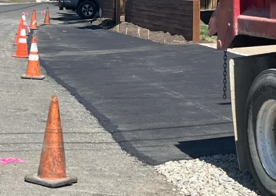 Freshly paved driveway with traffic cones and a red truck on a sunny day.